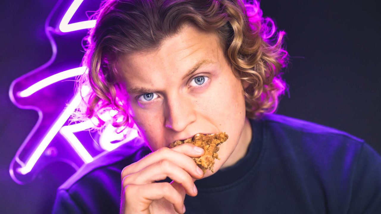 Model Eating fried chicken in front of neon sign